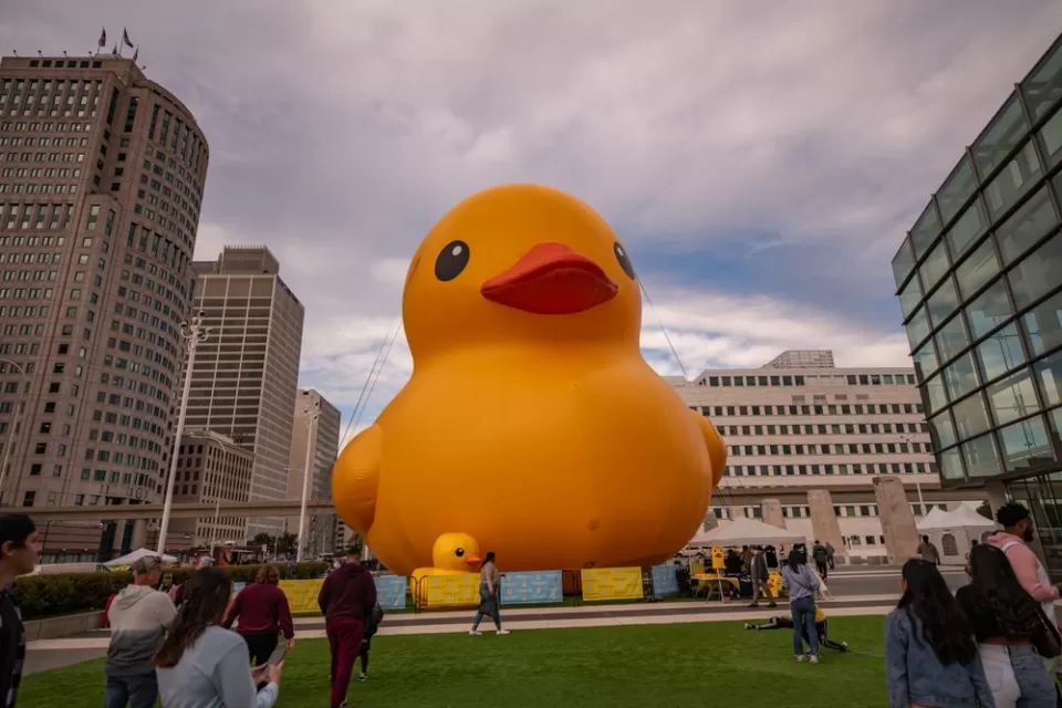 Giant inflatable yellow rubber ducky placed in plaza at Huntington Place, Detroit with pedestrians milling around